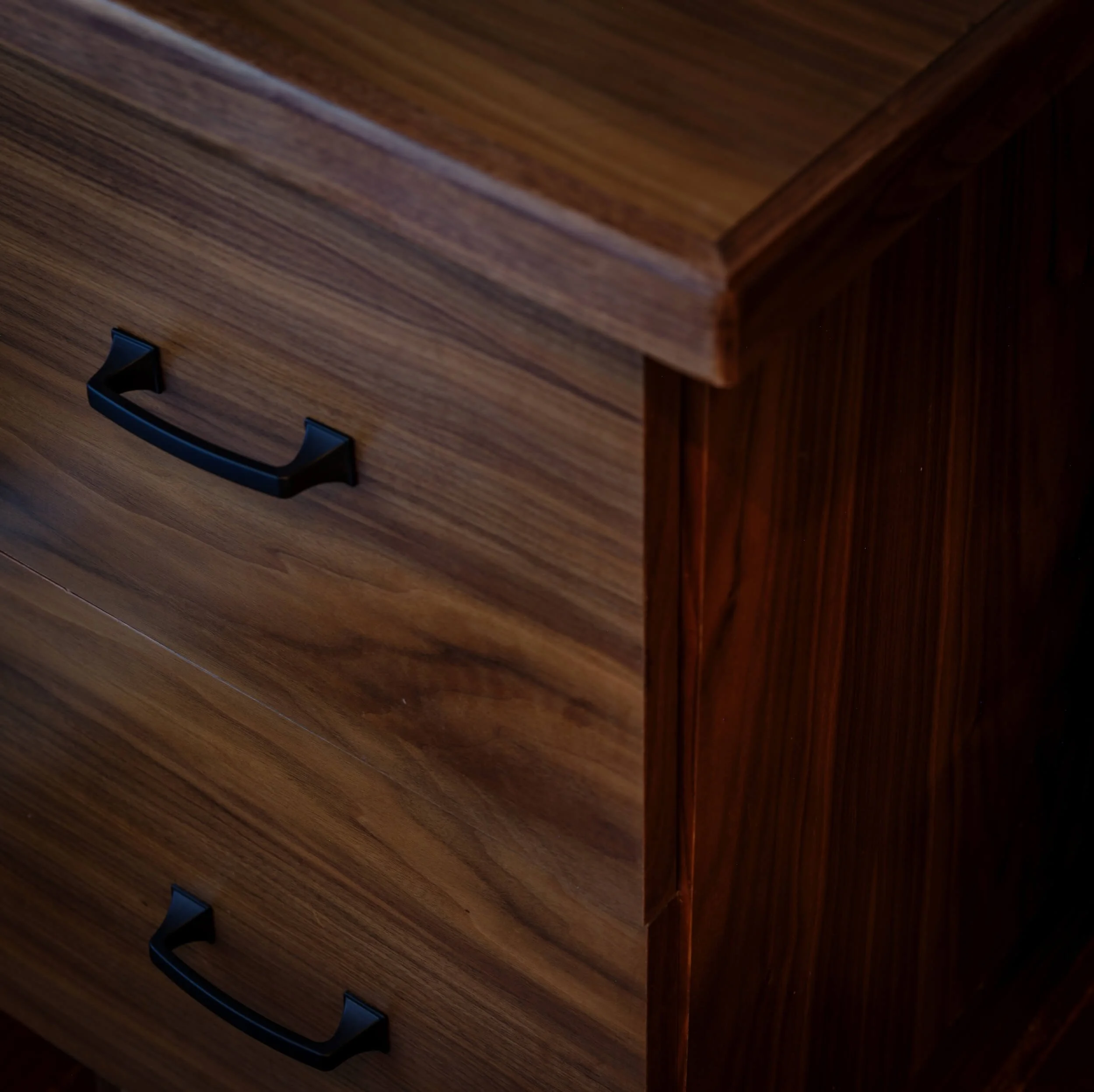 Close-up of a wooden desk with a black handle on a drawer