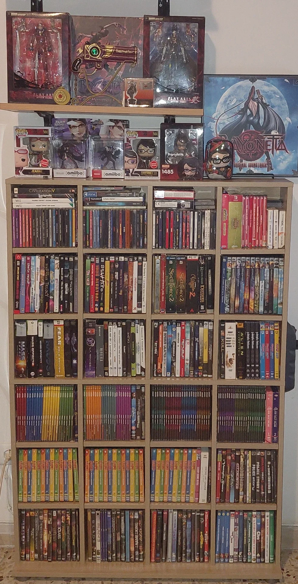 Libreria piena di videogiochi retrò con una parte della collezione di Bayonetta sopra