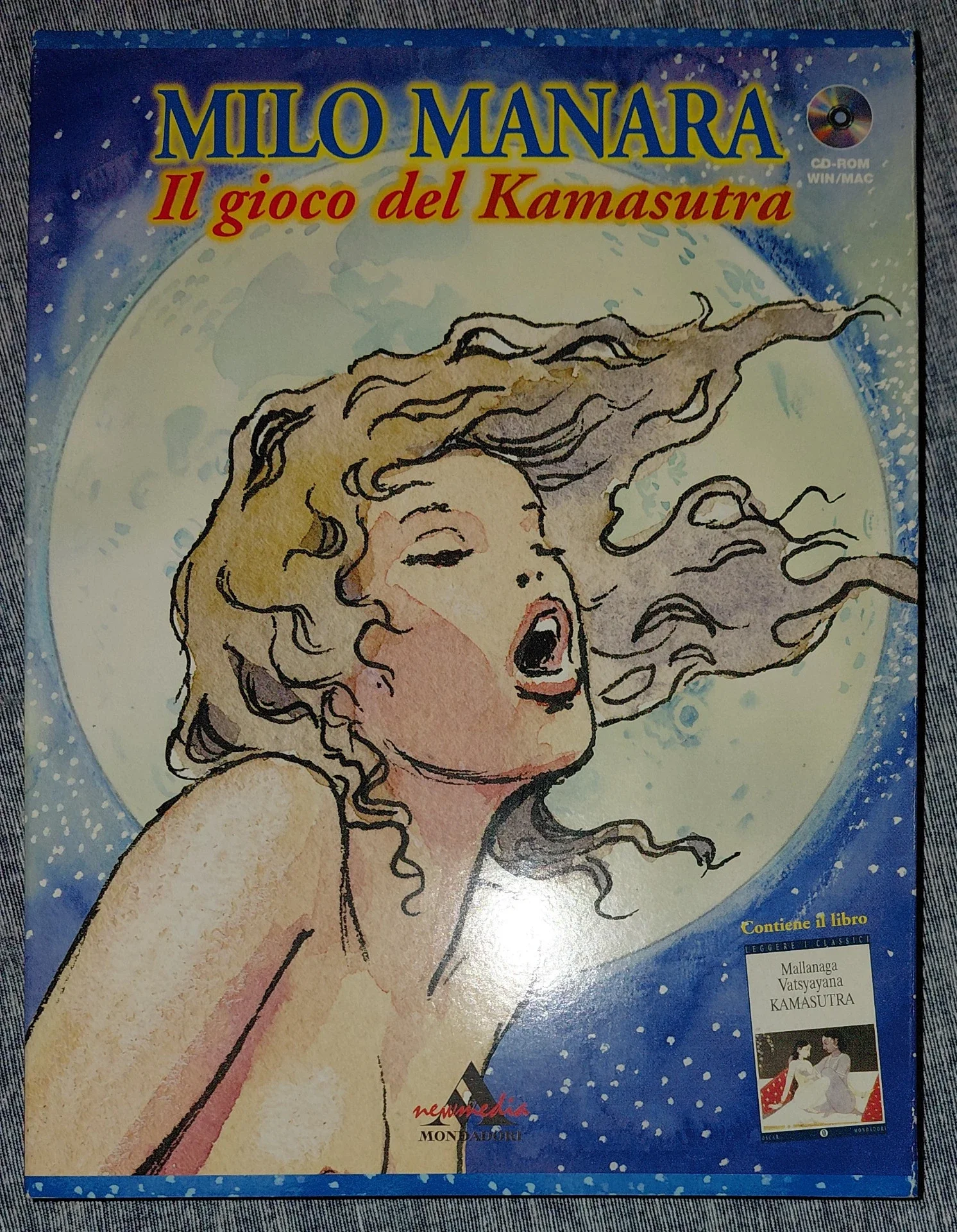 Copertina di un libro con illustrazione di una donna con i capelli sciolti davanti ad una grande luna. Il titolo è "Milo Manara Il gioco del Kamasutra" e contiene un CD-ROM.