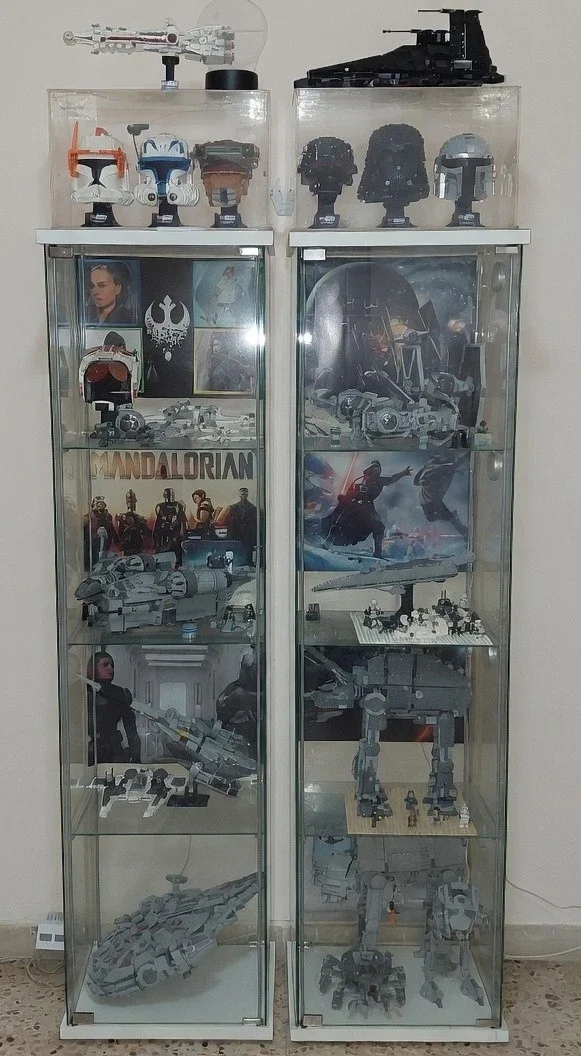 Una vetrina con modellini e oggetti della serie Star Wars, tra cui casco di Darth Vader, veicoli spaziali, figure di personaggi e stampe di scene di battaglia.