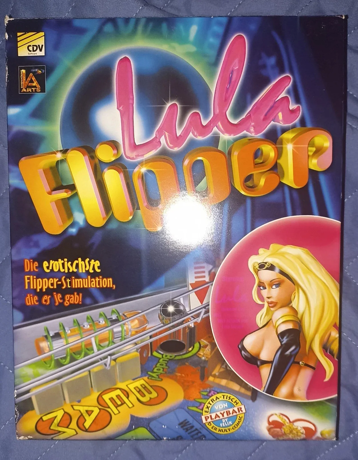 Copertina di un gioco chiamato 'Lida Flipper' con testi in tedesco, un'immagine di una donna con capelli biondi vestita in modo provocante, e un'illustrazione di una macchina da flipper con vari dettagli e scritte colorate.