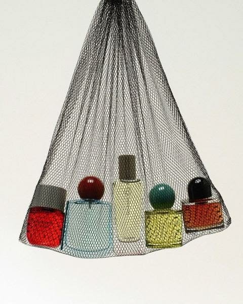 A wire mesh cone-shaped container holding various colored cosmetic bottles and containers.