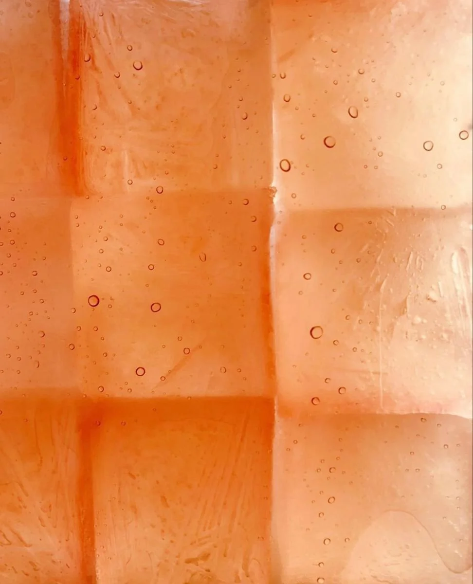Close-up of peach ice cubes with tiny air bubbles inside.
