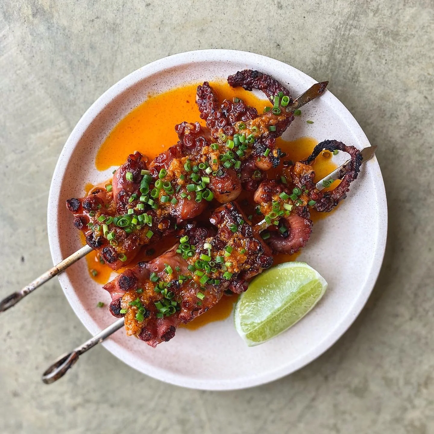 Grilled Fremantle octopus with nduja butter and lime, plated on stoneware