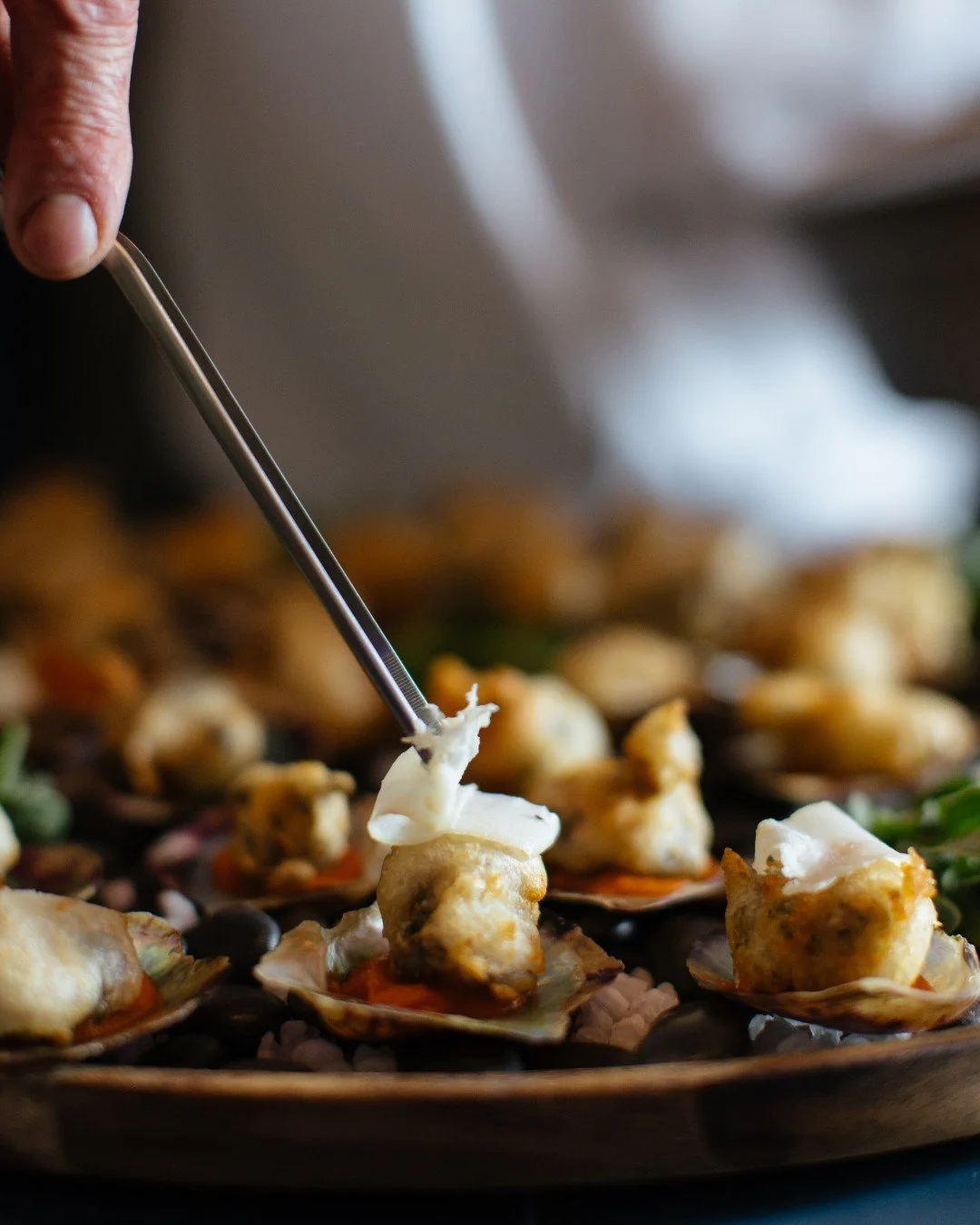 Chef tweezing finishing touches onto a Akoya popcorn, served on a chorizo and capsicum pure and topped with lardo  at a Studio Cibo private dining event