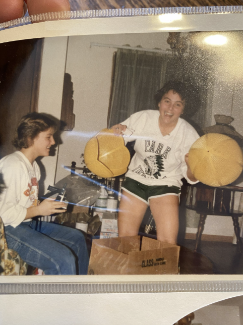 Two women holding yellow lamp shades while setting up a childhood bedroom that inspired the founder’s love of home.