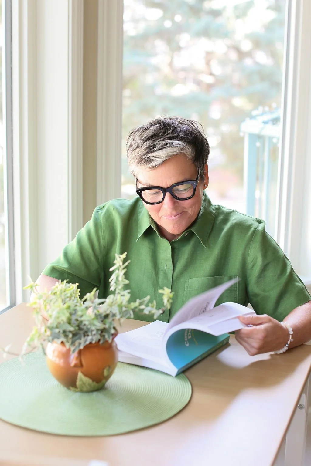 Michelle Hoff reading Compassionate Decluttering book at a table