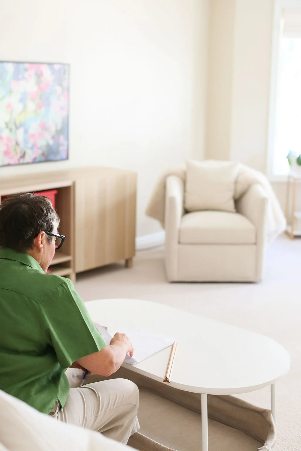 Home coach taking notes in a calm living room, representing the coaching support behind a team approach to decluttering.