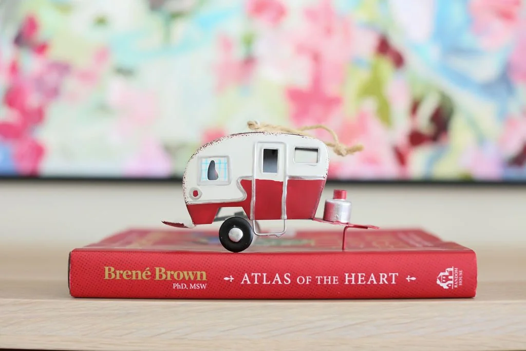 A small camper figurine on a book about emotions, representing the emotional side of decluttering and home coaching.
