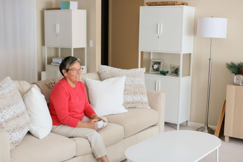 Woman sitting in a calm living room, representing the mental load of home and why decluttering can feel so hard.