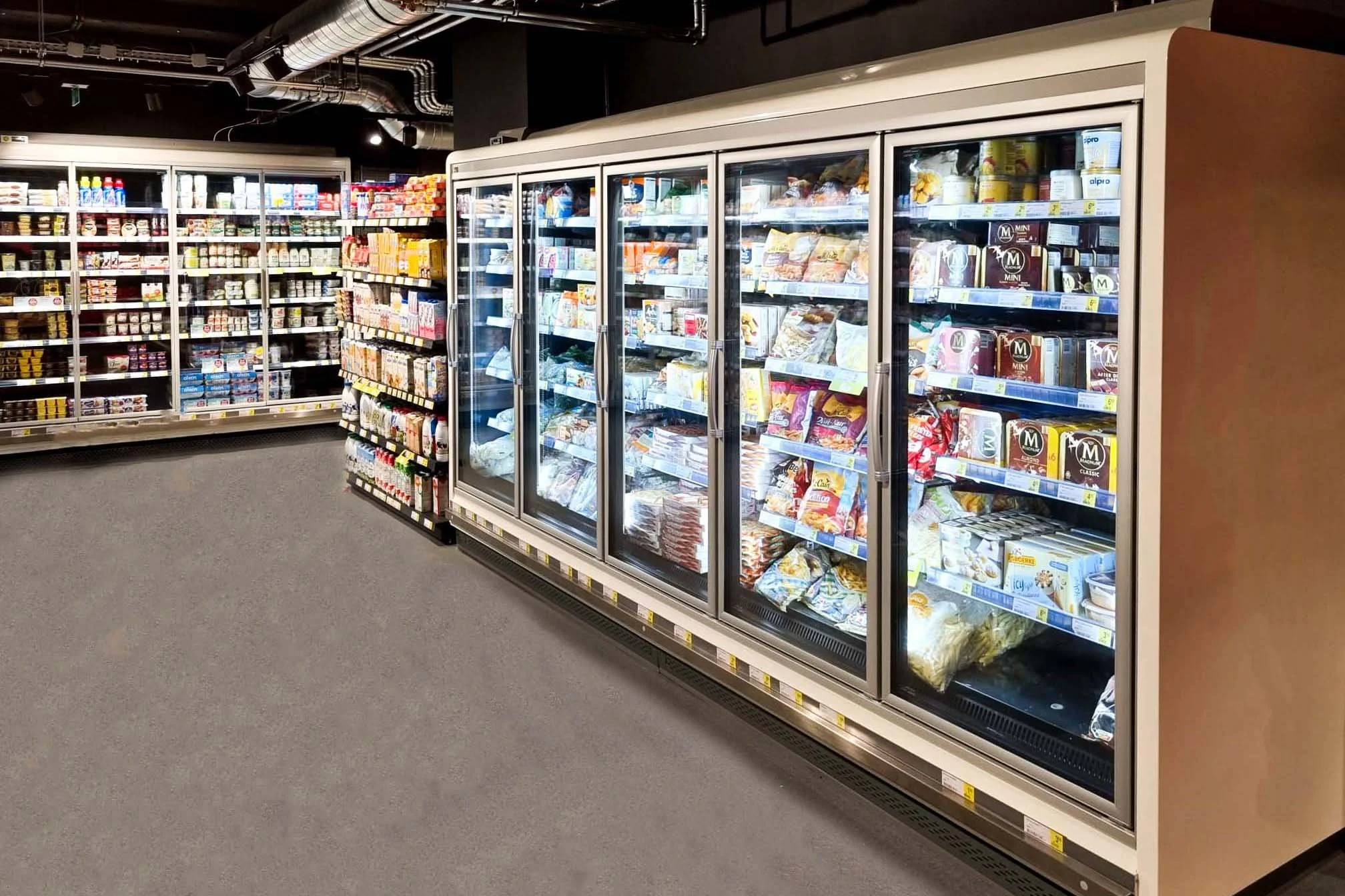 MarCELL PRO can easily monitor refrigerated grocery store aisle with glass door freezers stocked with frozen foods, milk, and ice cream, in a supermarket.