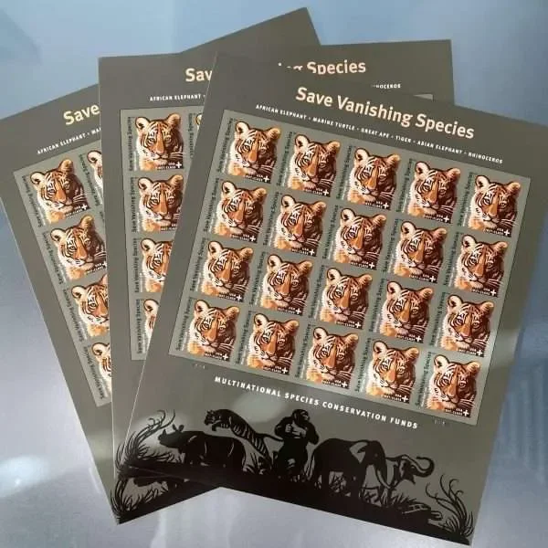 Three sheets of paper, each with printed stamps featuring a tiger's face, titled 'Save Vanishing Species.' The sheets also have silhouettes of African wildlife at the bottom.
