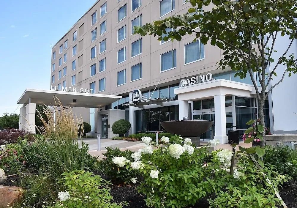 Exterior view of a hotel with the names Merigot and Casino on the building, surrounded by landscaped greenery and flowers.