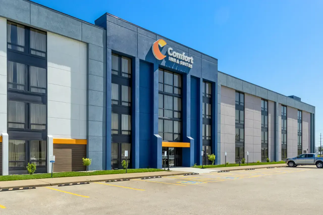 Exterior of a Comfort Inn & Suites hotel with a modern design, large windows, and a parking lot in front.