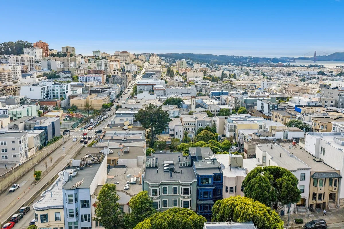 A cityscape view of San Francisco including houses, buildings, and the Golden Gate Bridge in the background.