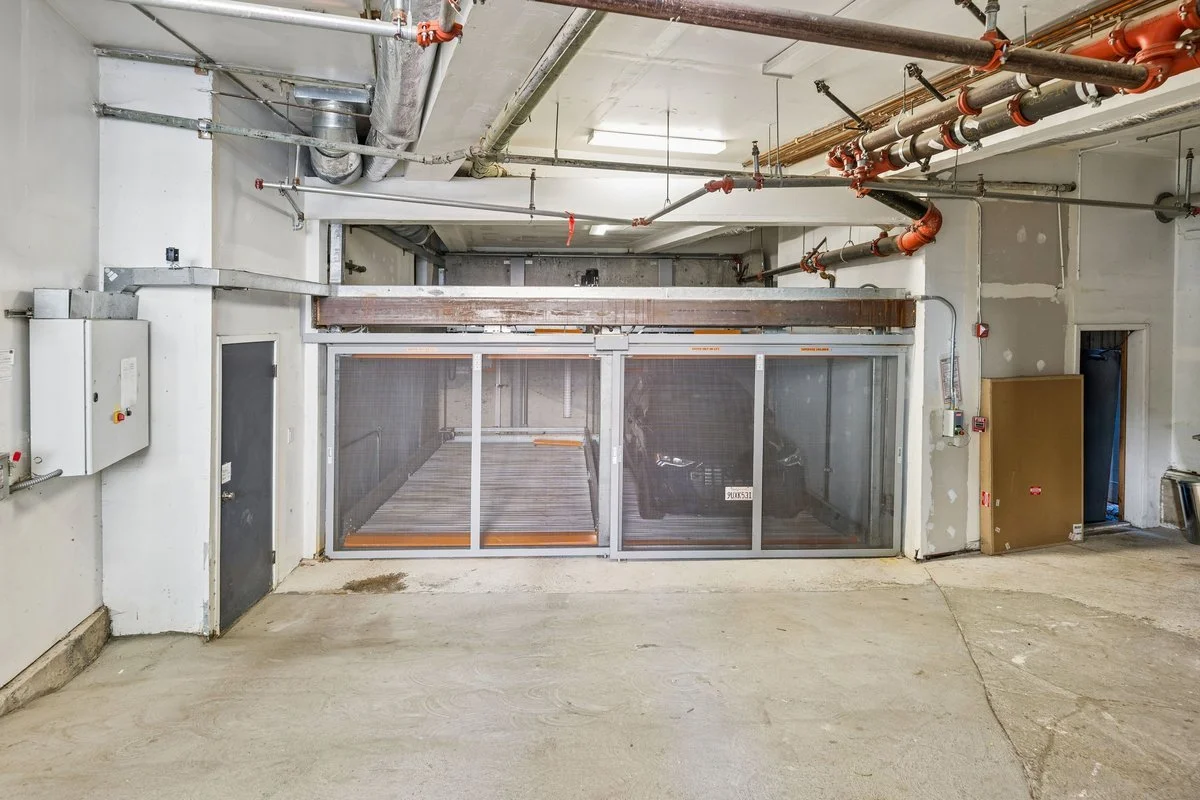An empty underground parking garage with a gated elevator or lift.