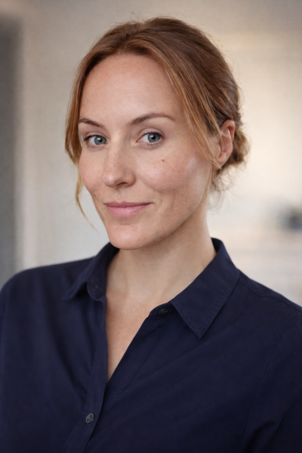 Close-up portrait of Teale Hamilton, a woman with red hair and blue eyes, wearing a dark blue shirt, smiling softly