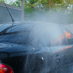 A black car being washed with water and soap spray