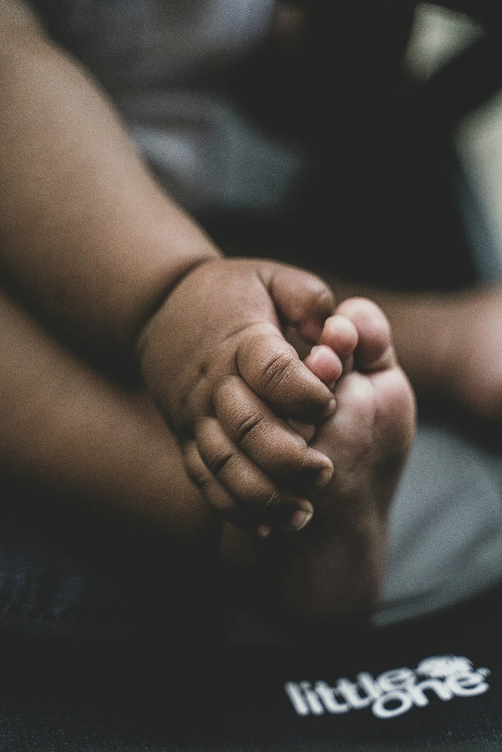 Close-up of two children's hands holding each other, one darker and one lighter skin tone.