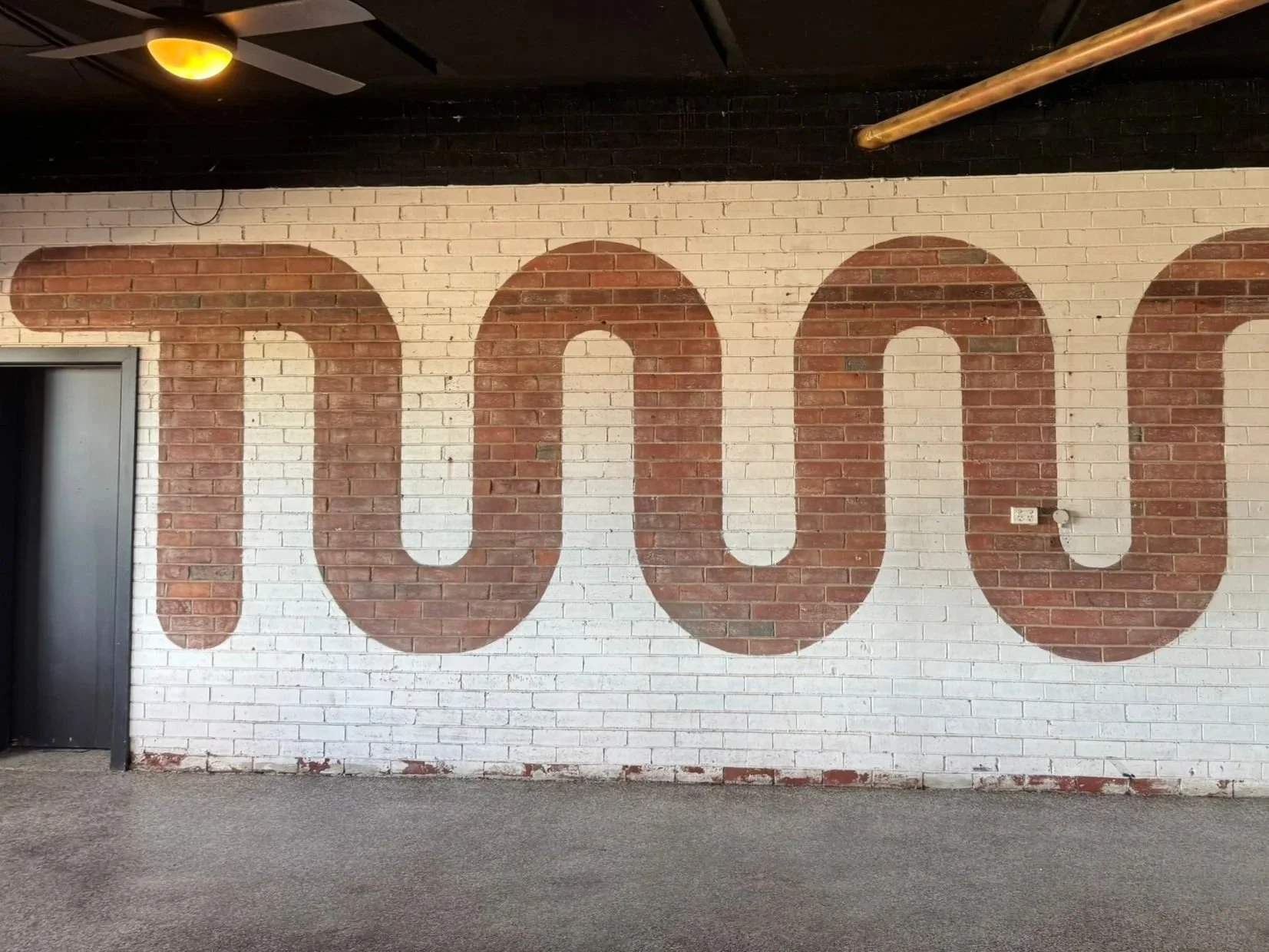 A white brick wall with the number '100' painted on it in large red-brown letters.