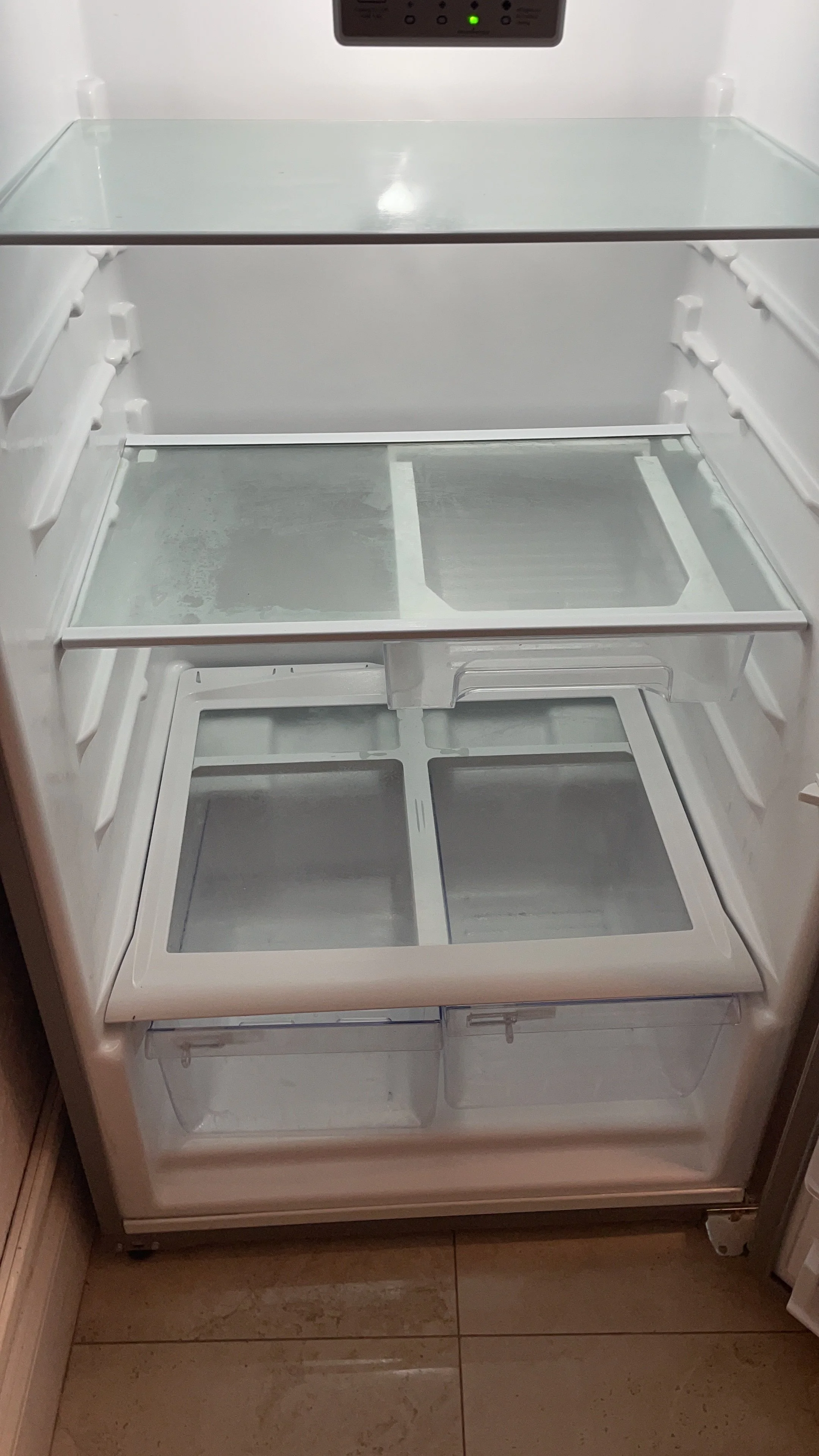 Empty refrigerator with glass shelves and drawers inside.