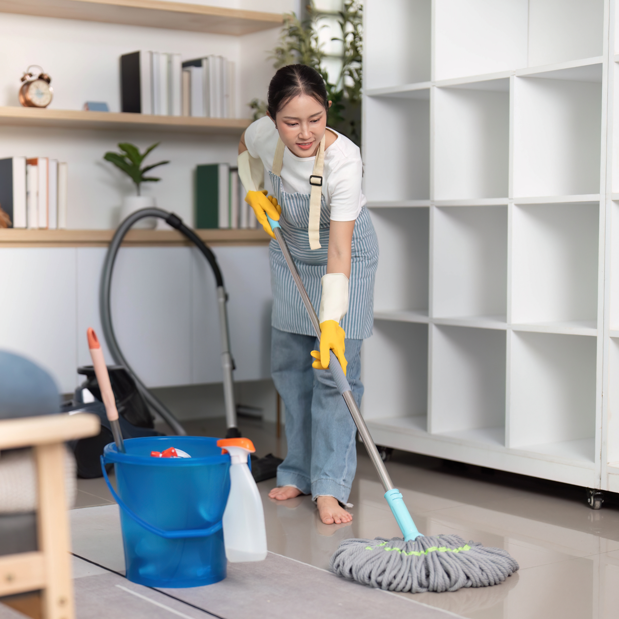 A woman cleaning a floor with a mop in a modern, well-lit room.