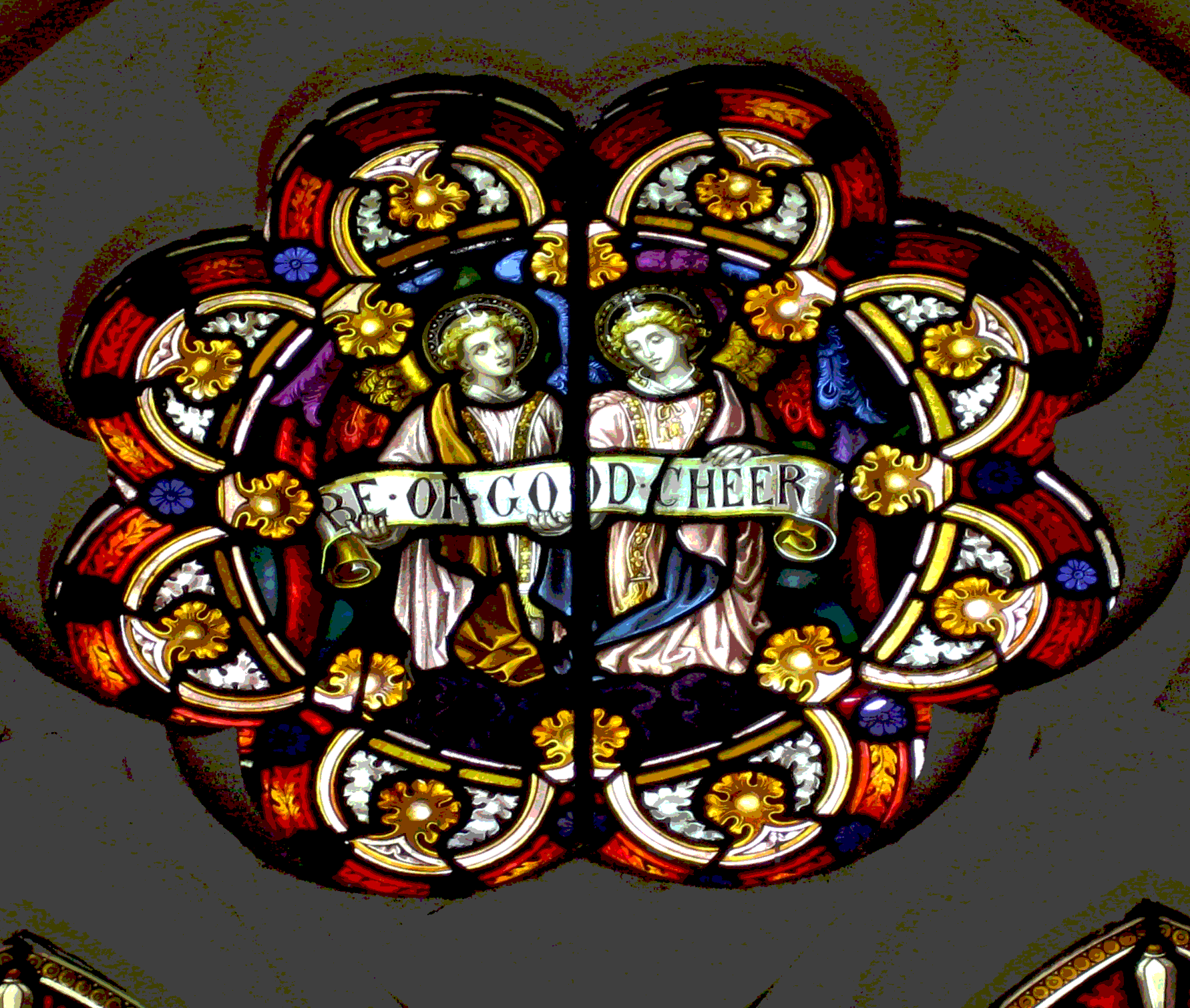 Colorful stained glass window depicting two angels holding a banner that reads 'REJOICE OF GOD AND HEIR', surrounded by intricate floral and geometric patterns.