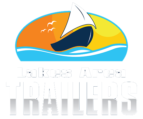 Logo of Lakes Area Trailers featuring a sailboat on water, with a sunset or sunrise background in warm colors.