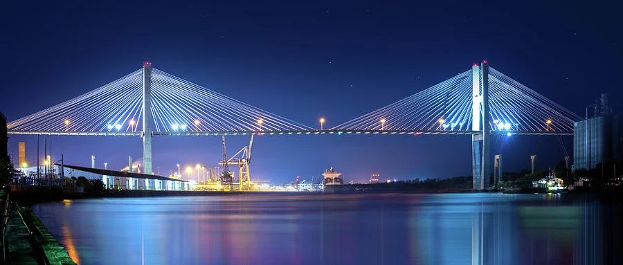 Night view of a illuminated cable-stayed bridge over a calm water body.