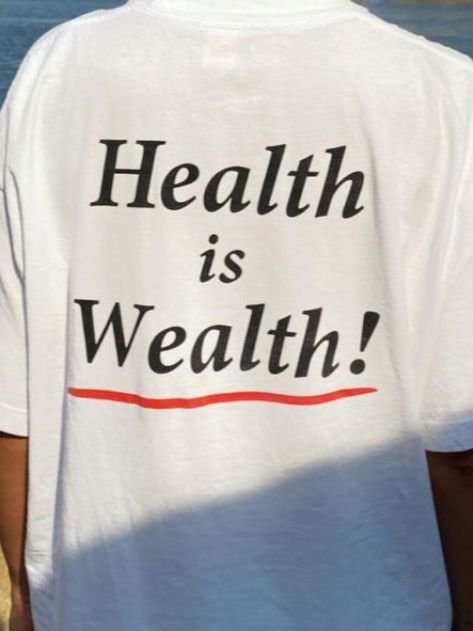Back view of a person wearing a white T-shirt with the phrase "Health is Wealth!" printed on it, with a red underline.