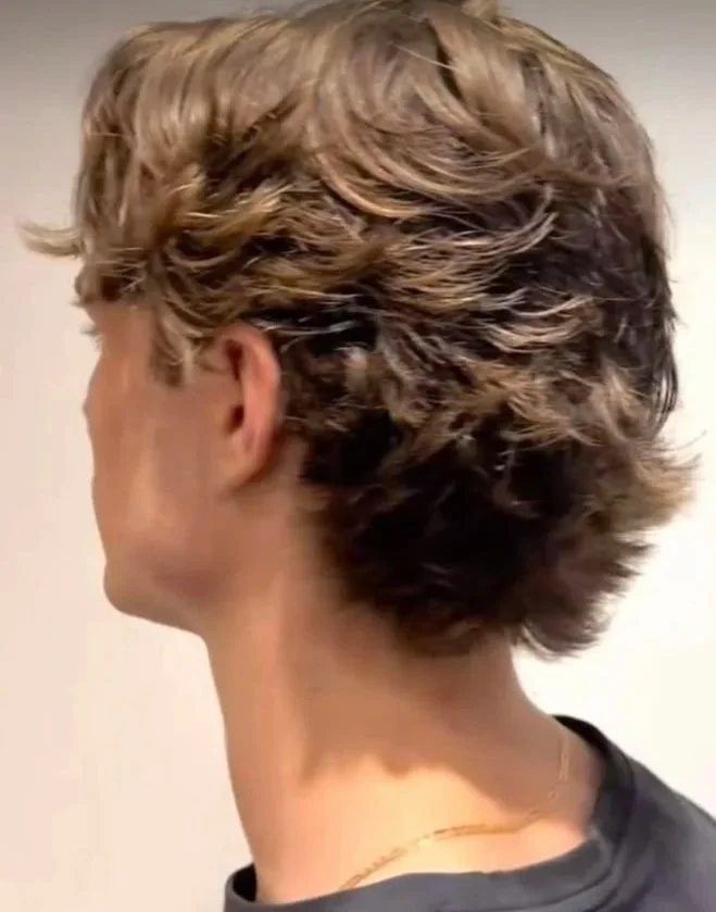 Side view of a person with short, wavy, light brown hair.