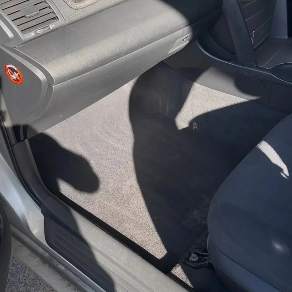 Vehicle interior after professional detailing showing a clean carpeted floor and refreshed cabin