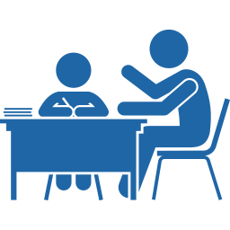 A person sitting at a desk with a laptop, and another person standing and talking to them, in a professional setting