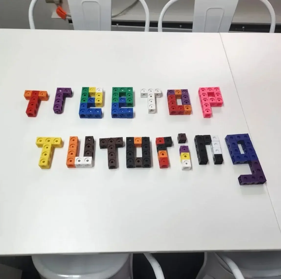 Colorful plastic blocks spelling out 'TIETÄ' on a white table.