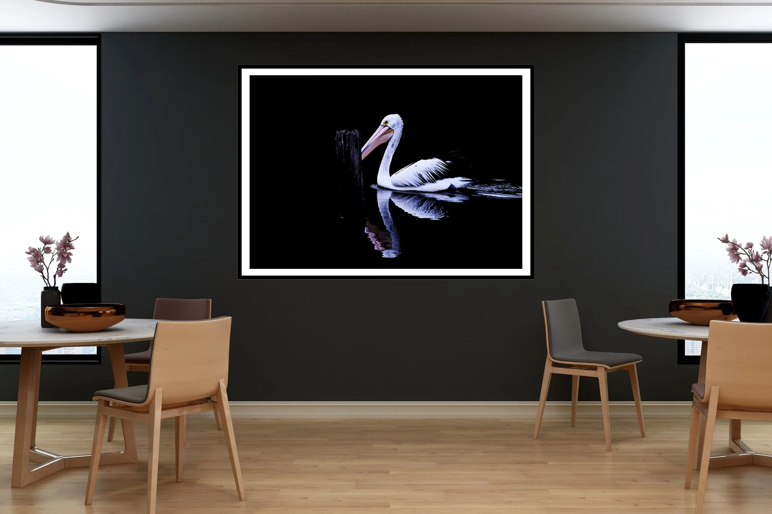A striking minimalist photograph of a black and white Pelican set against a deep black background