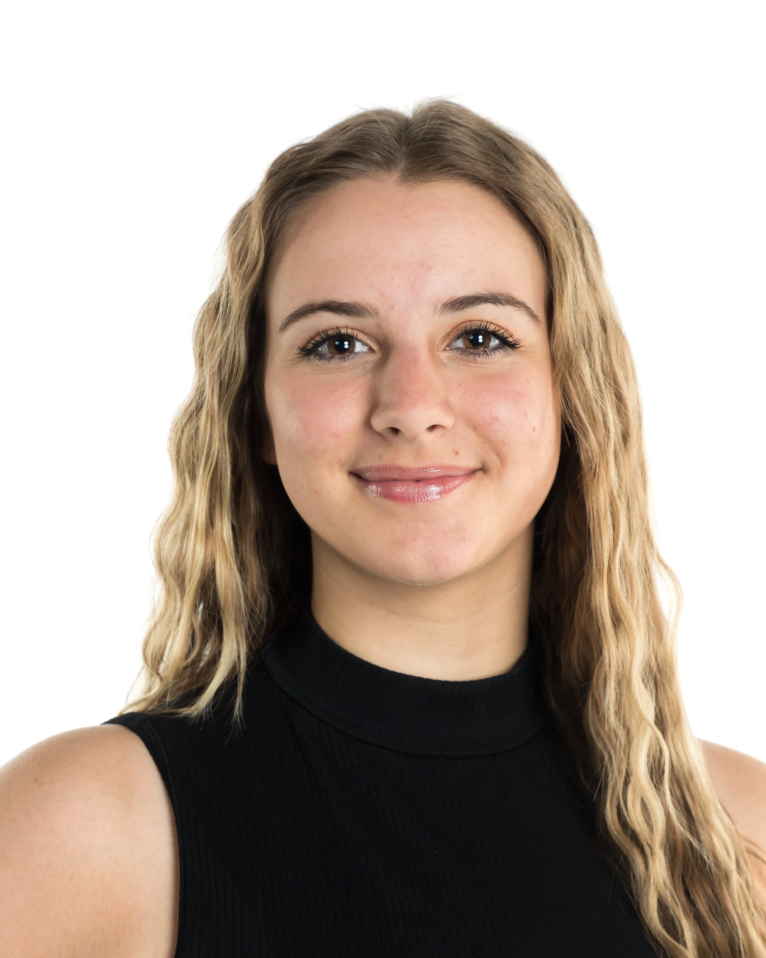 Close-up of a young woman with wavy blonde hair, wearing a black sleeveless top, smiling slightly against a white background.