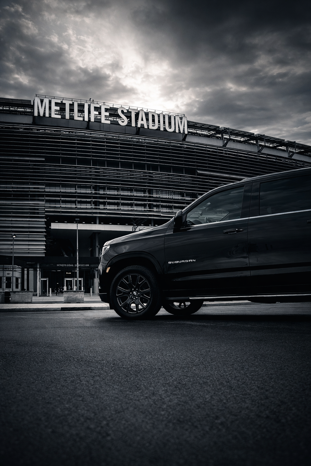 A black SUV parked outside MetLife Stadium on a cloudy day.