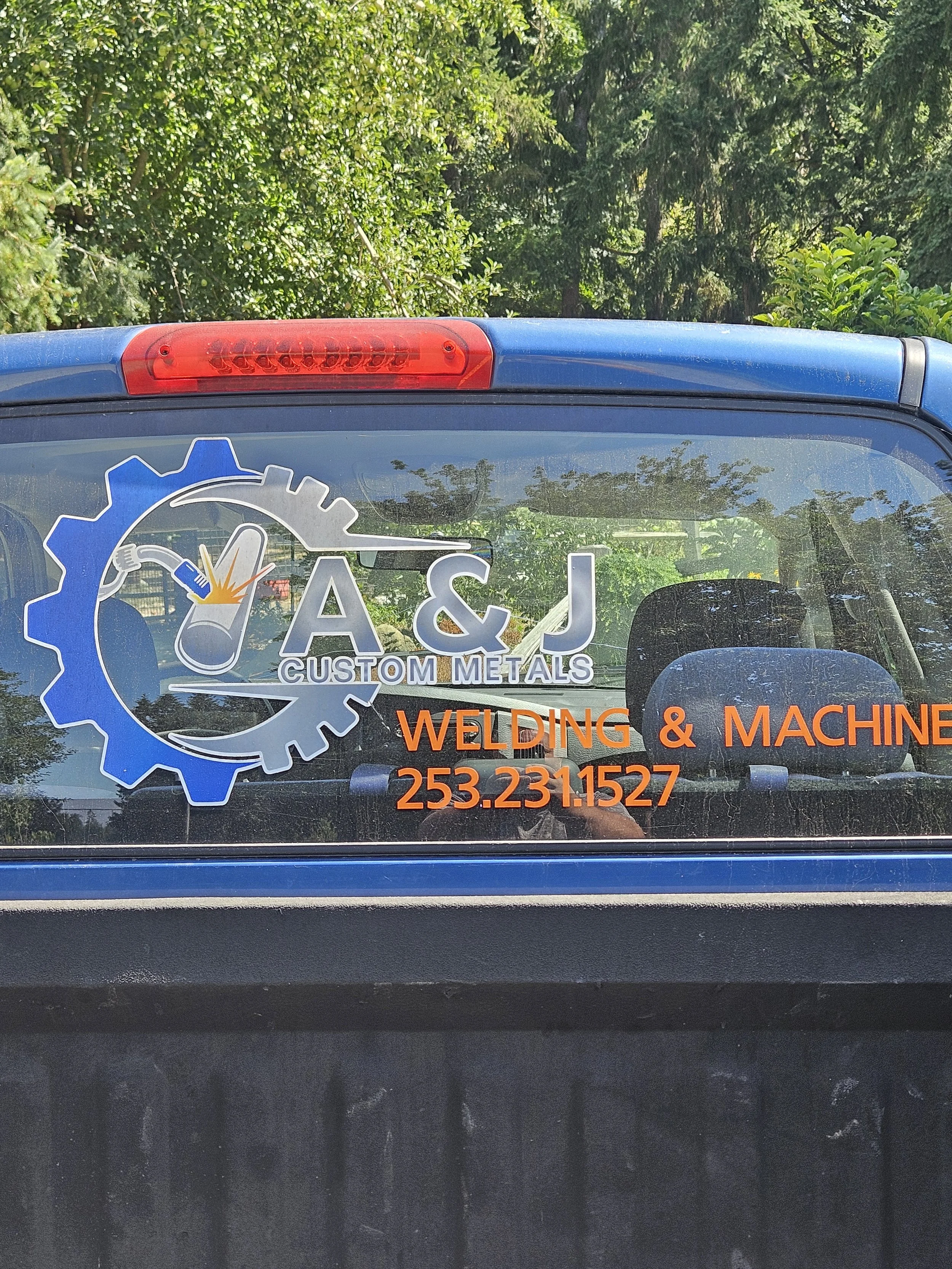 A&J Custom Metals truck door decal with company logo, Welding & Machine, and phone number 253-231-1527.