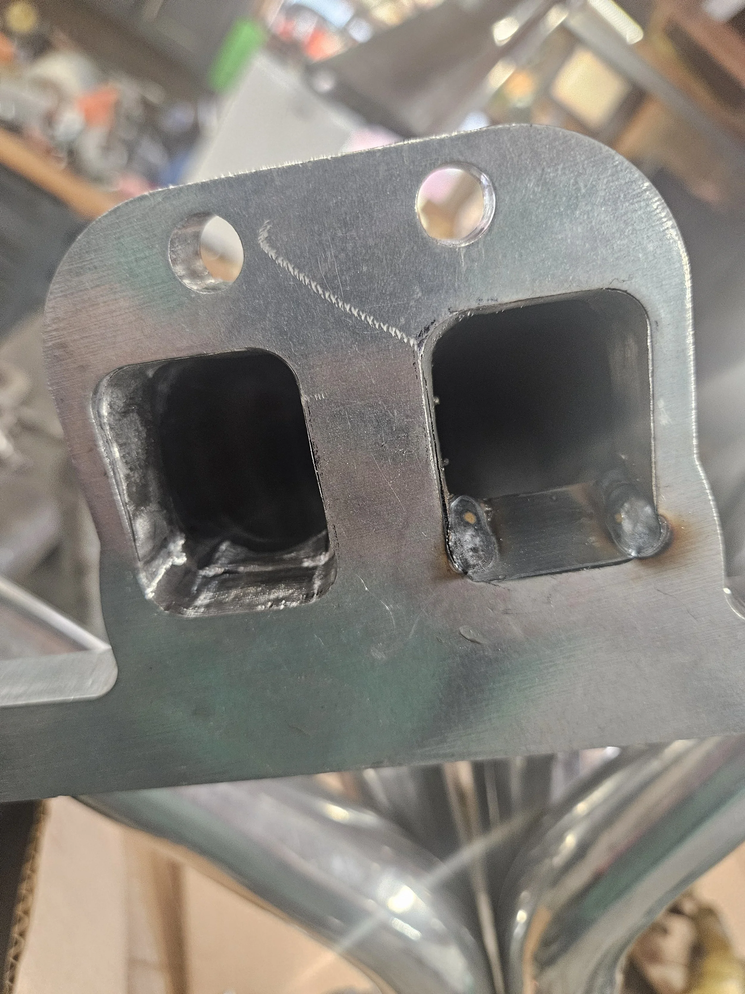 Custom fabricated metal flange plate with welded square ports and mounting holes, made by A&J Custom Metals.