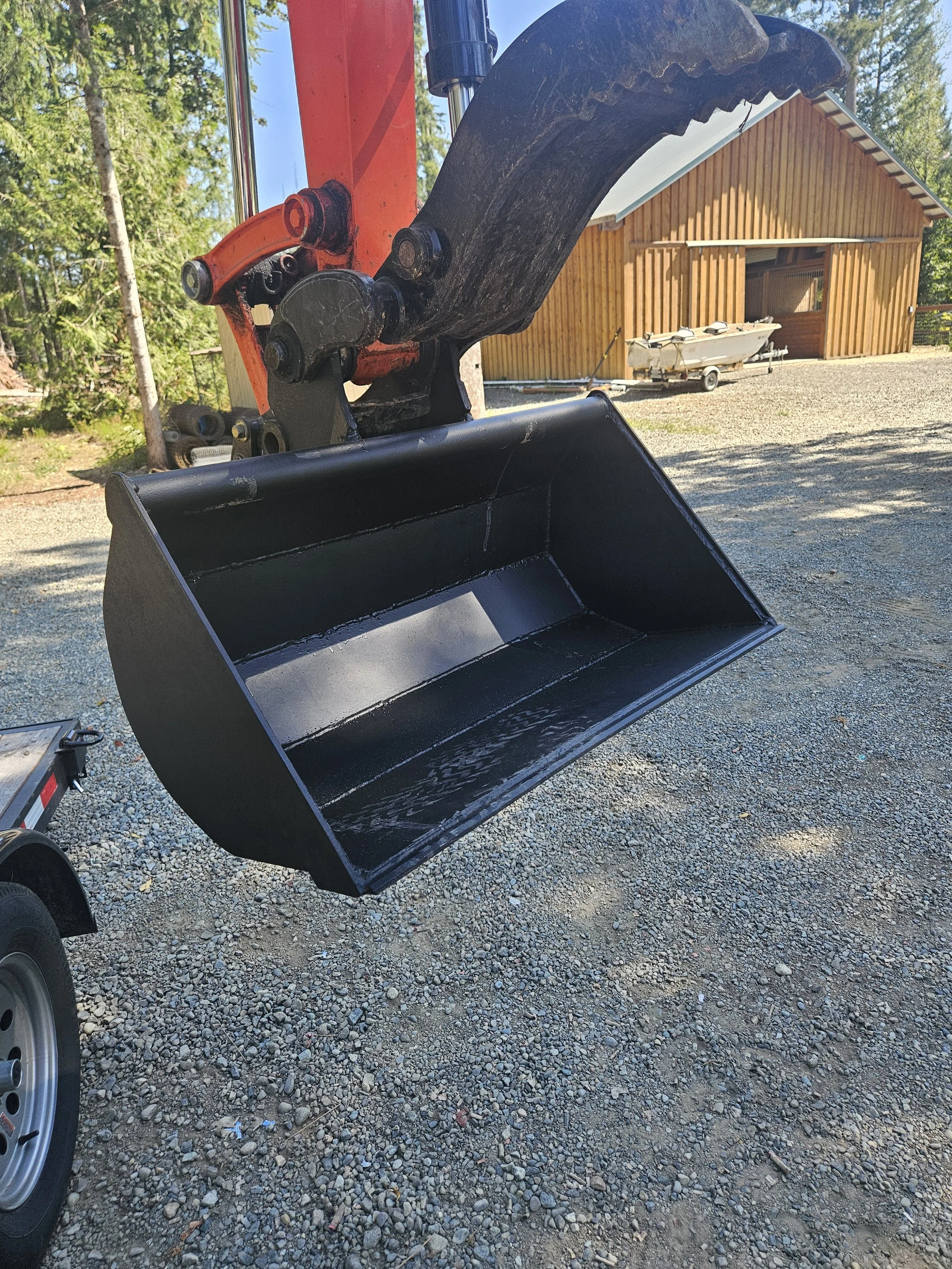 Black excavator bucket attachment fabricated by A&J Custom Metals, shown outdoors in Graham, WA.