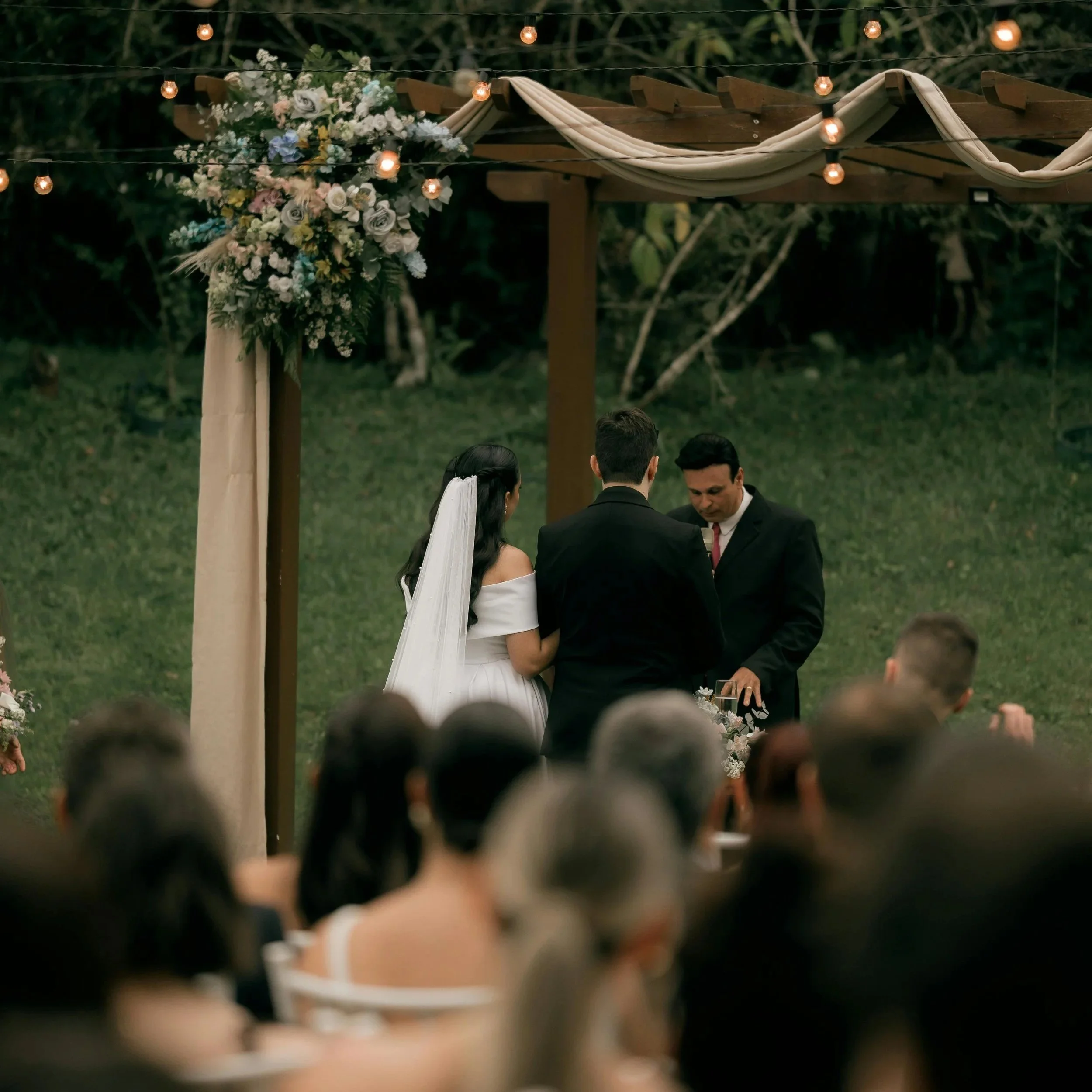 Bride and groom at their wedding ceremony. Fairy lights on aisle arch way.