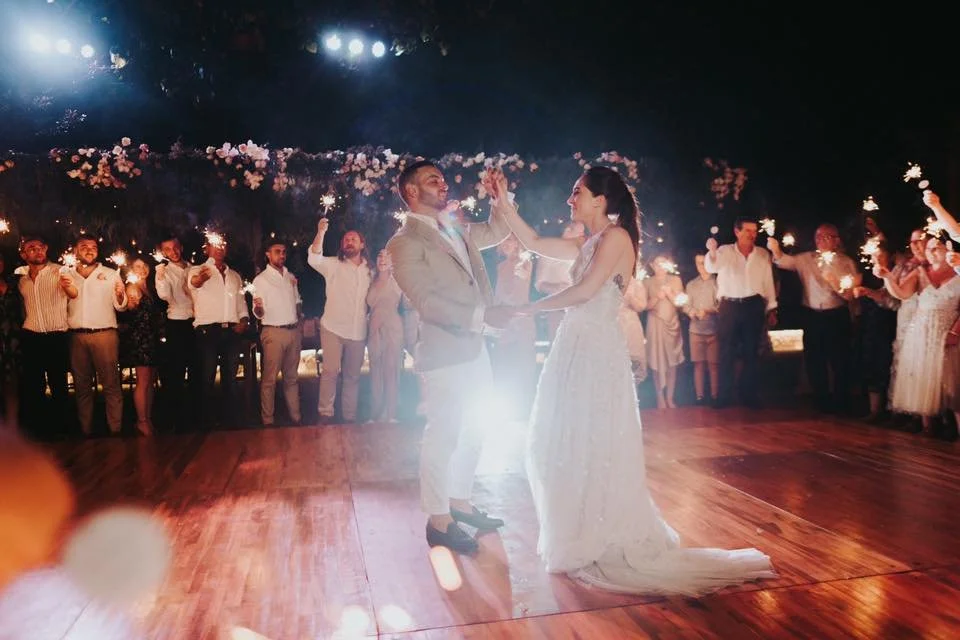 Couple dancing at wedding reception with sparklers and floral decorations in the background. First dance. Couples wedding dance. wedding celebration.