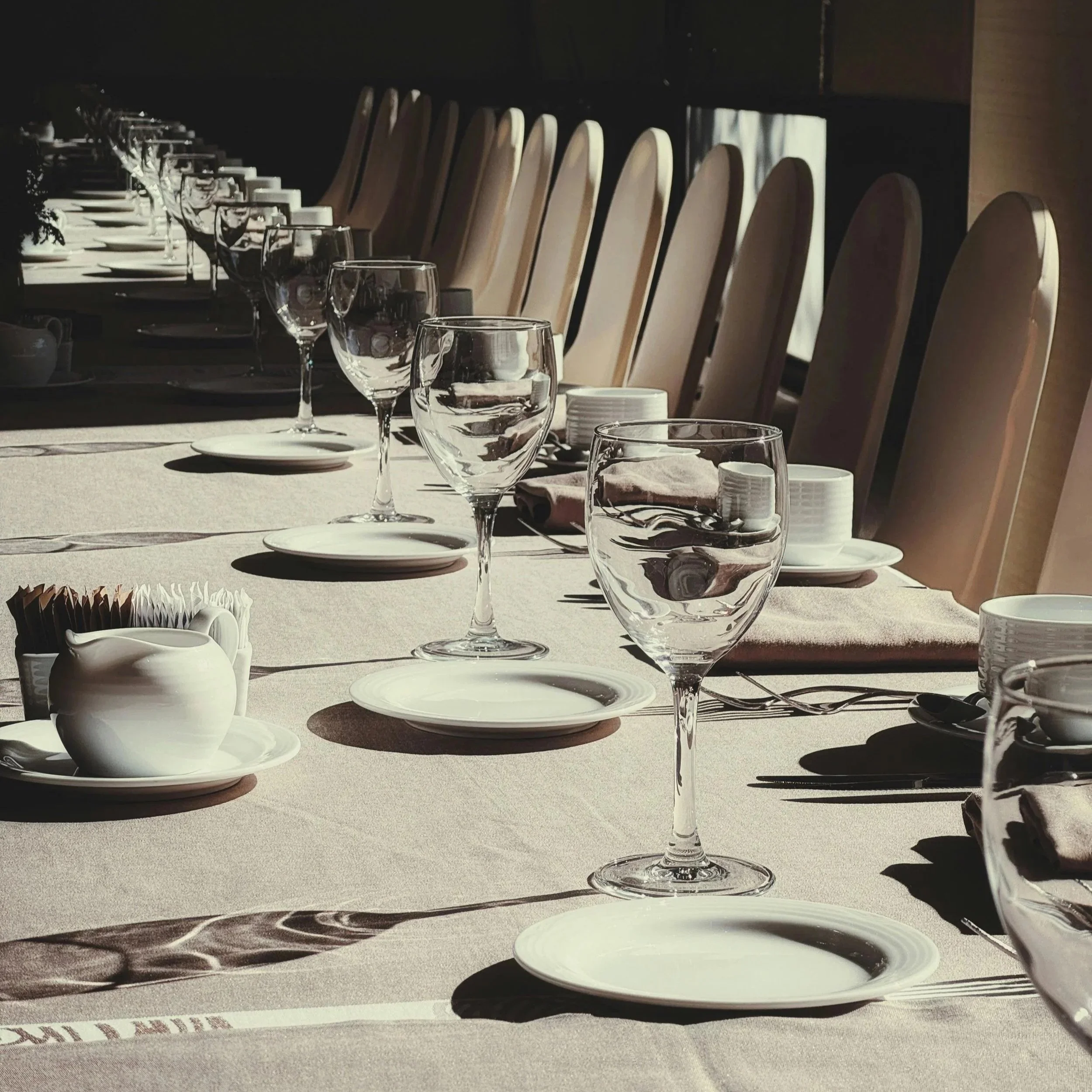 Wedding or corporate or private event dinner setting with wine glasses, tableware, formal dinner setting.