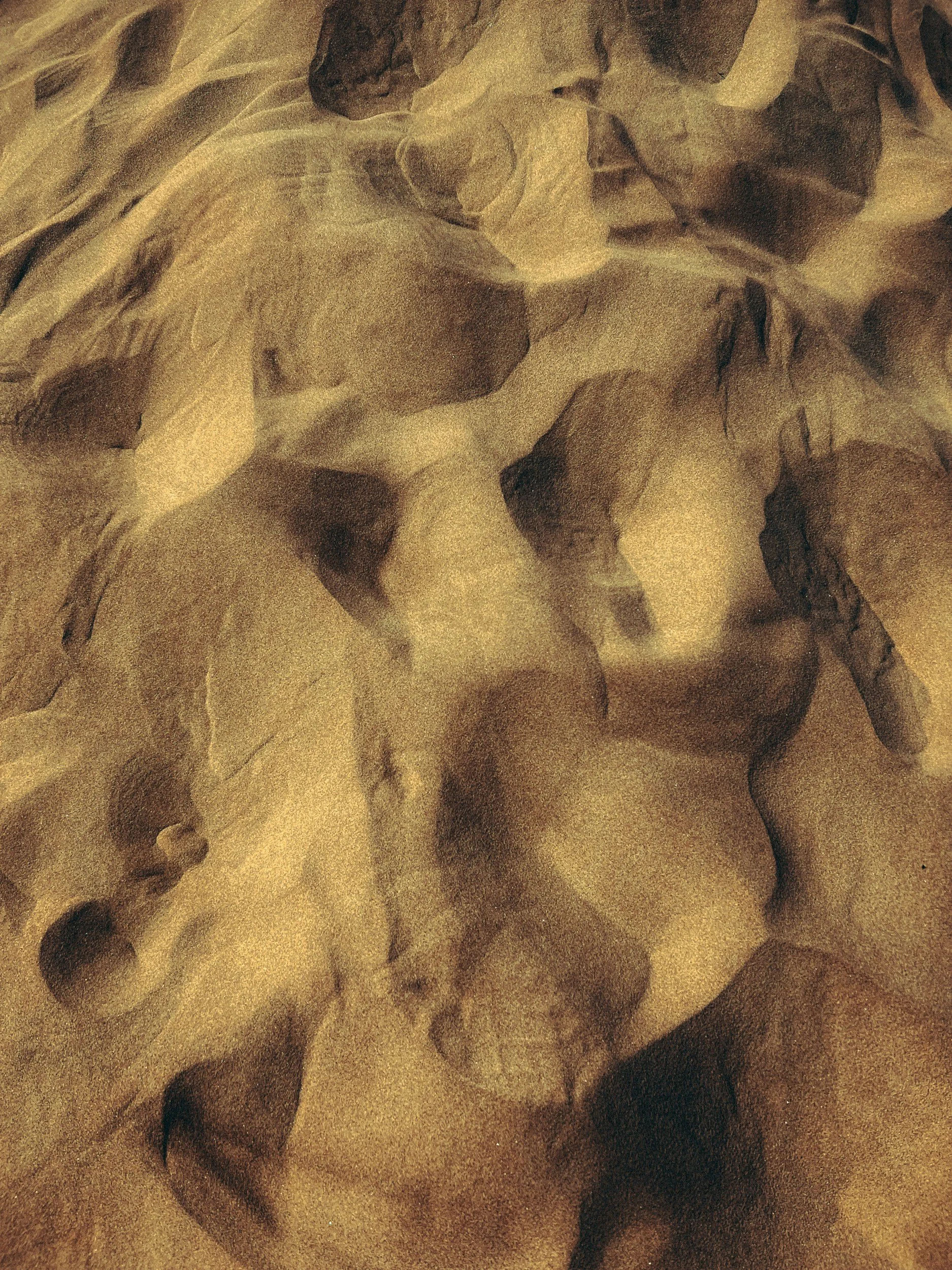 Close-up of brown and black swirling patterns on a textured surface, possibly marble or stone.