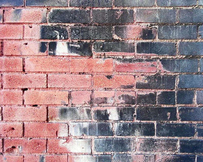 Fire-damaged brick covered in soot before laser cleaning