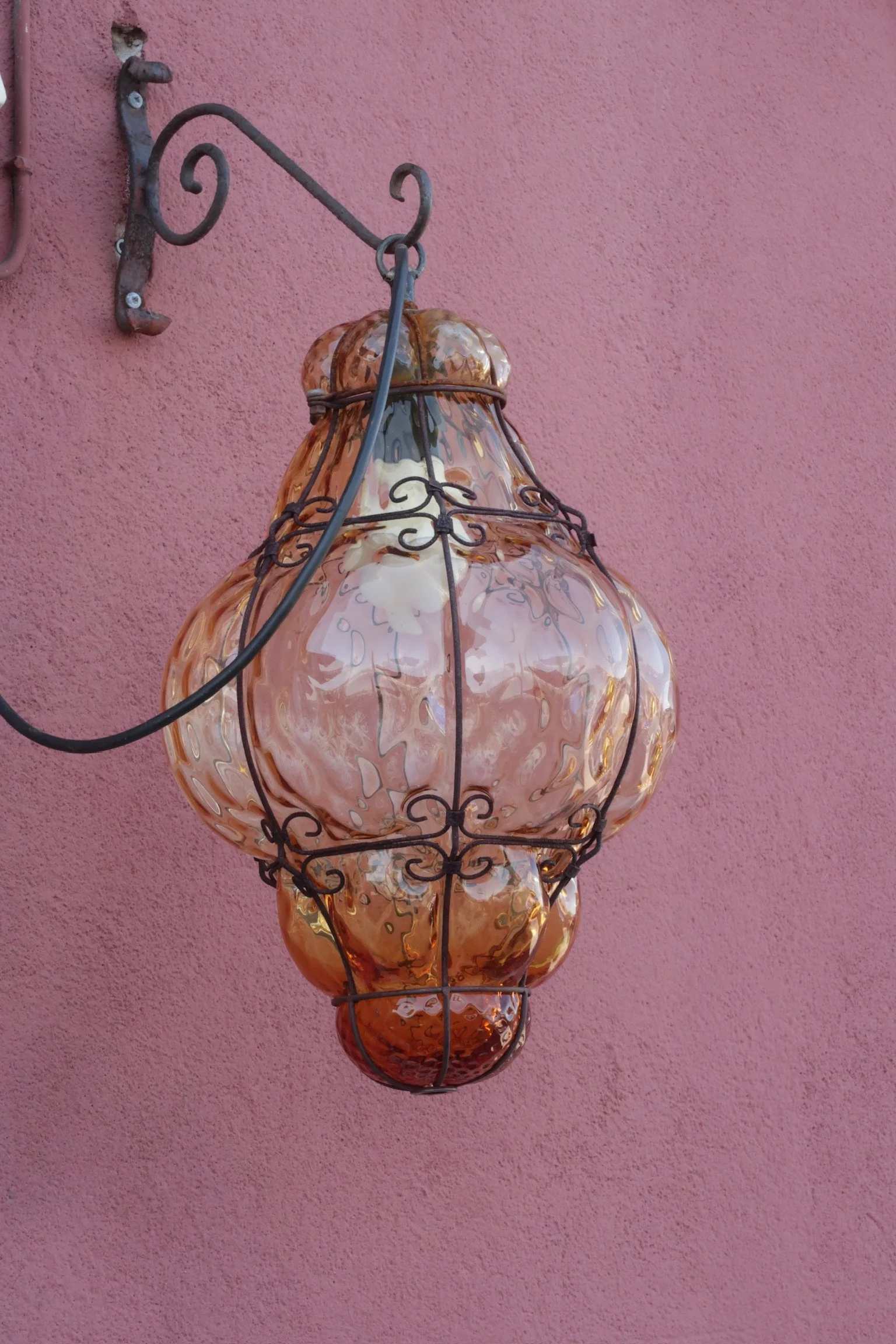 Decorative wall-mounted lamp with a pink textured wall background.