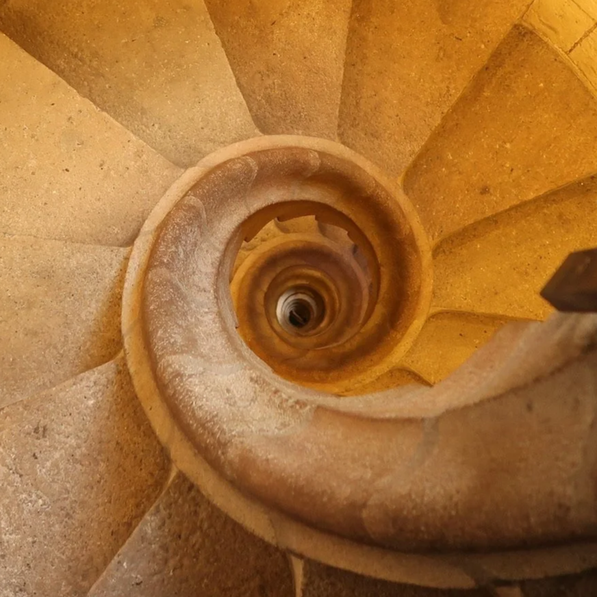 Looking down a spiraling stone staircase with a central column in the middle.
