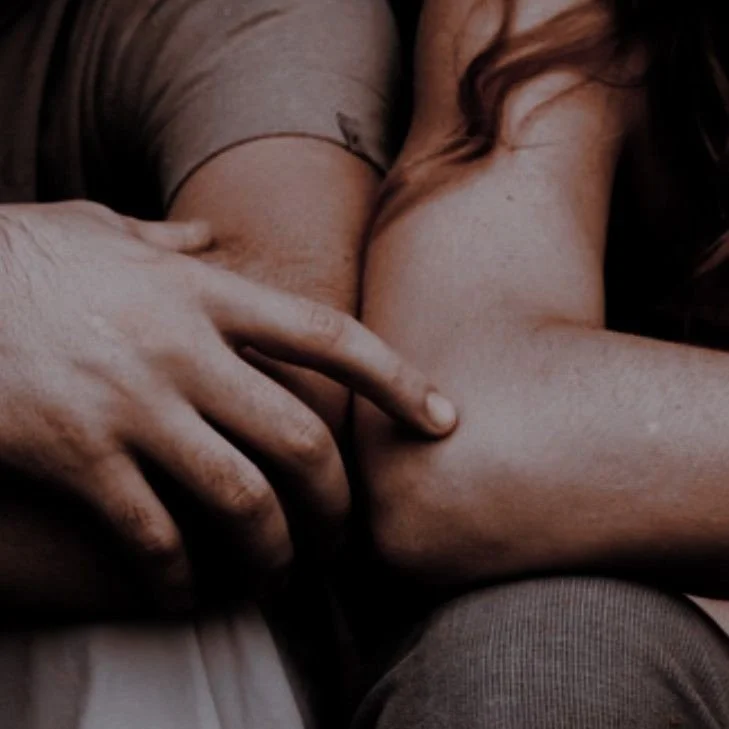 Close-up of two people embracing, focusing on their arms and hands.
