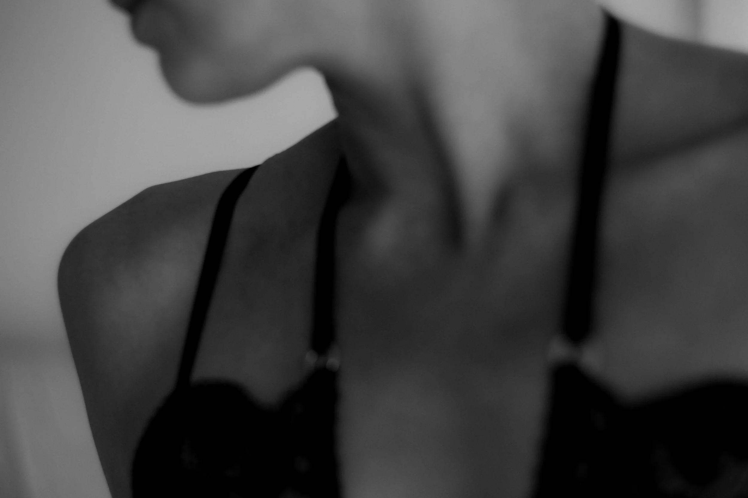Black and white blurred close-up of a person's face, shoulder, and neck, with a focus on the lips and nose area.