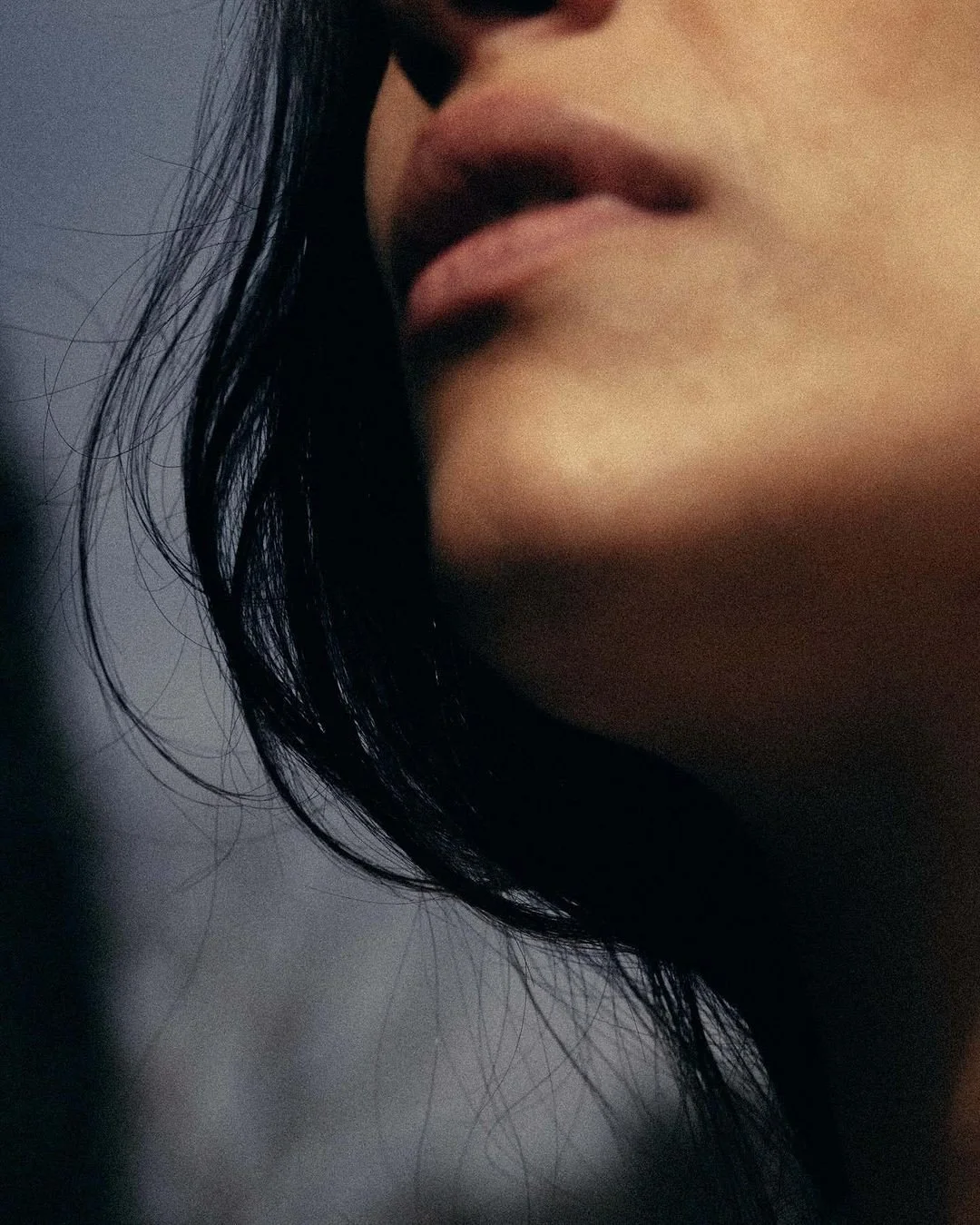 Close-up of a person's lips and chin with dark hair partially covering their face.